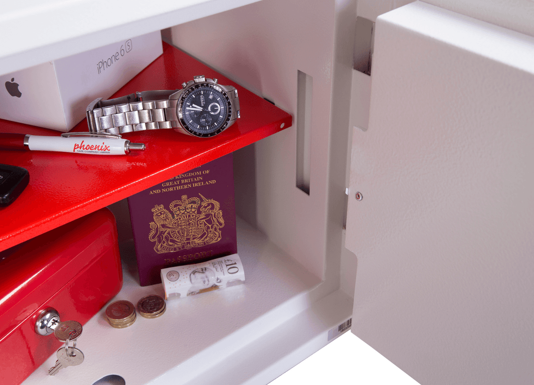 Open safe with valuables: watch, passport, cash, and electronics inside.